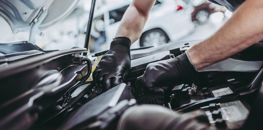 A Man Is Working On The Engine Of A Car With The Hood Open — Advanced Darwin Diesel Service In Darwin City, NT