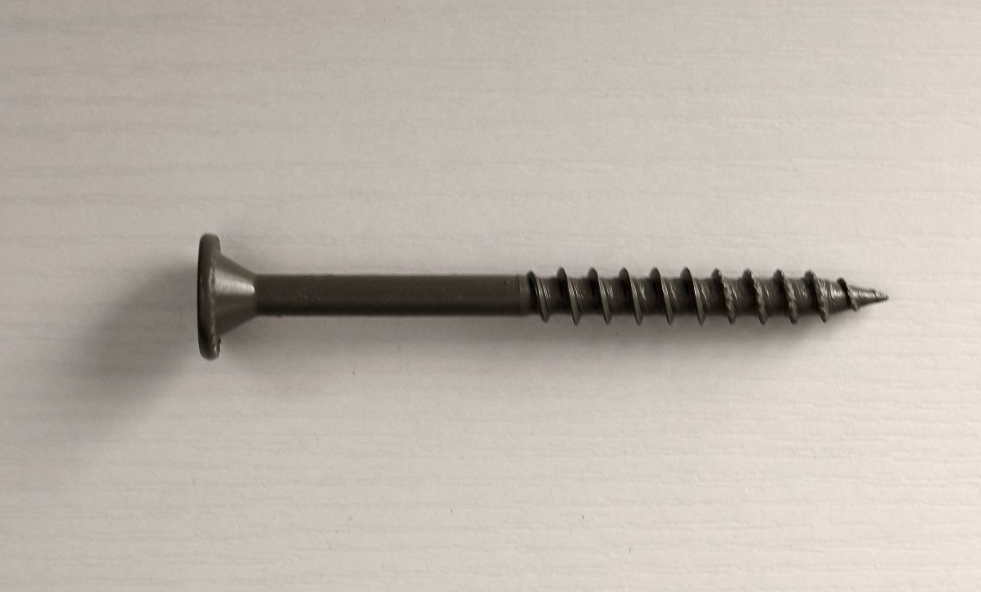 Black screw with flat head on a light textured background