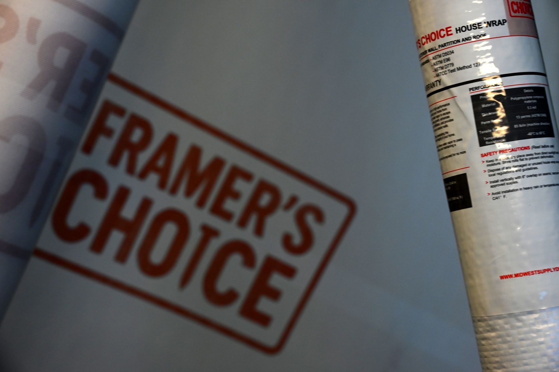 A can of spray paint beside a blurred red FRAMER'S CHOICE label on a gray surface.