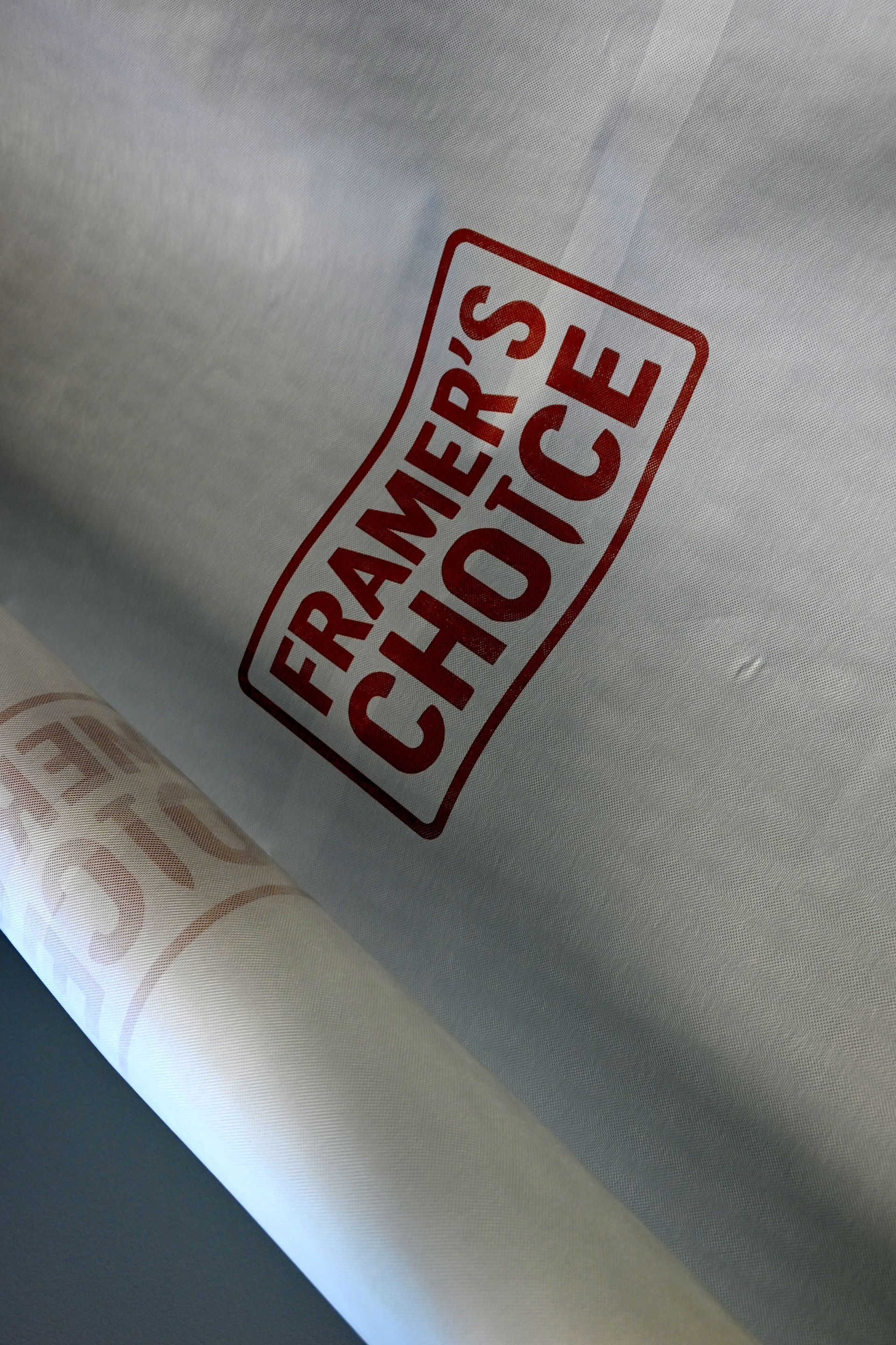 A can of spray paint beside a blurred red FRAMER'S CHOICE label on a gray surface.