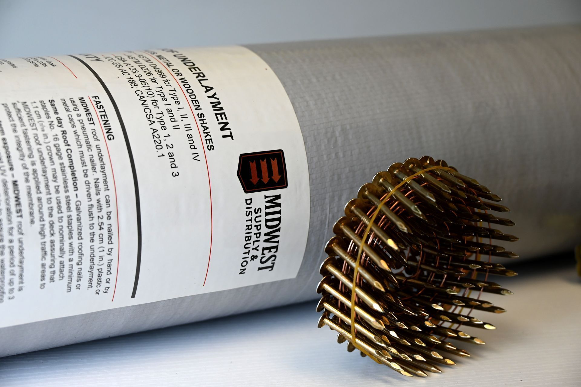 Roll of black anti-skid underlayment with a white product label on a gray background