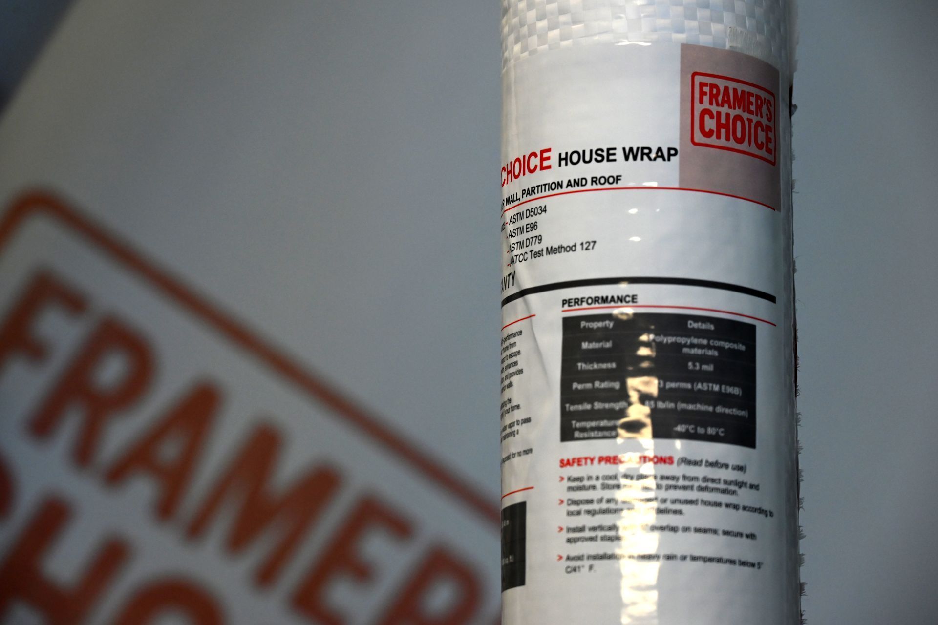 Roll of white house wrap with red and black label, partially wrapped in plastic
