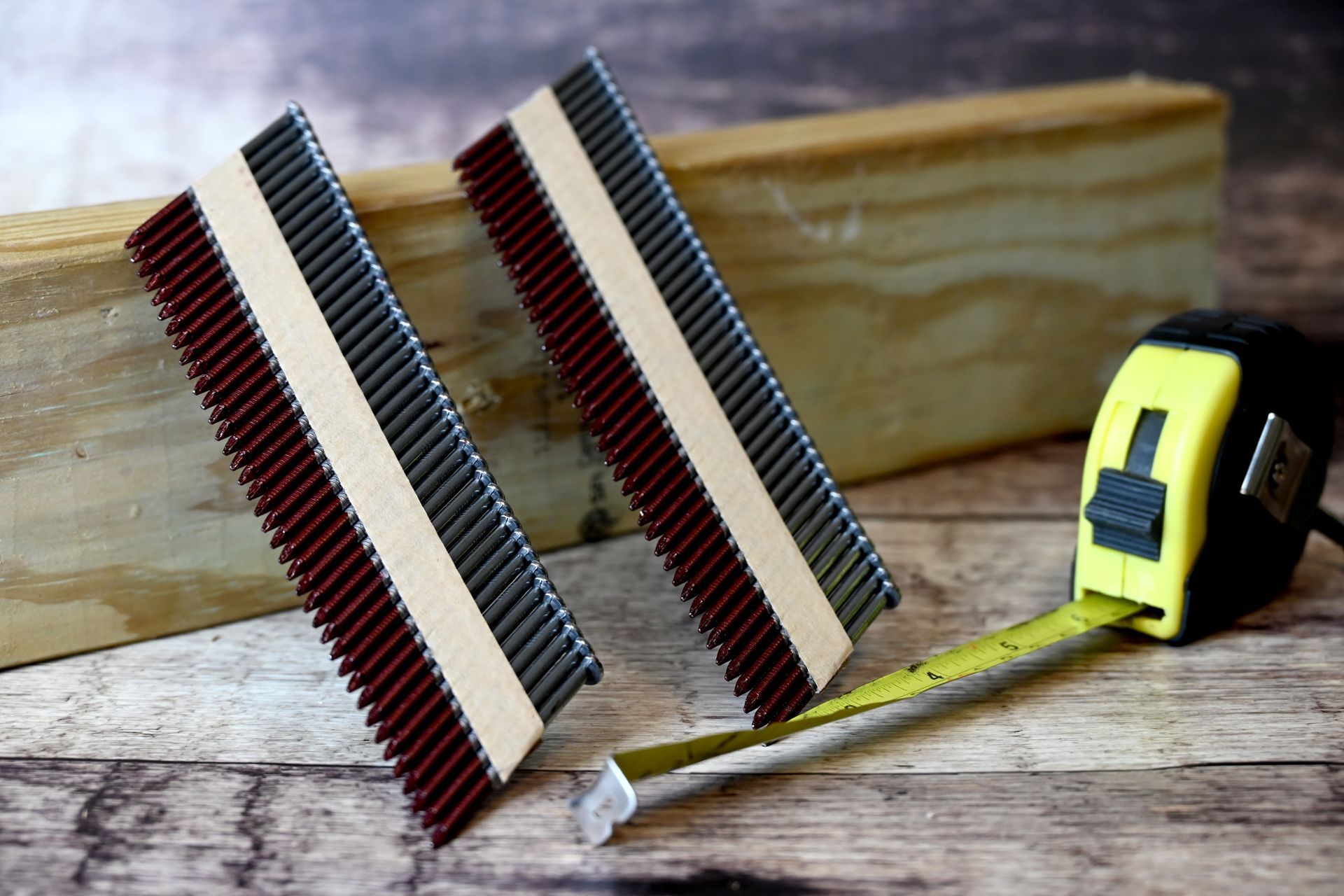 Two wooden hand saws with yellow tape measure on weathered wood, near a wooden block