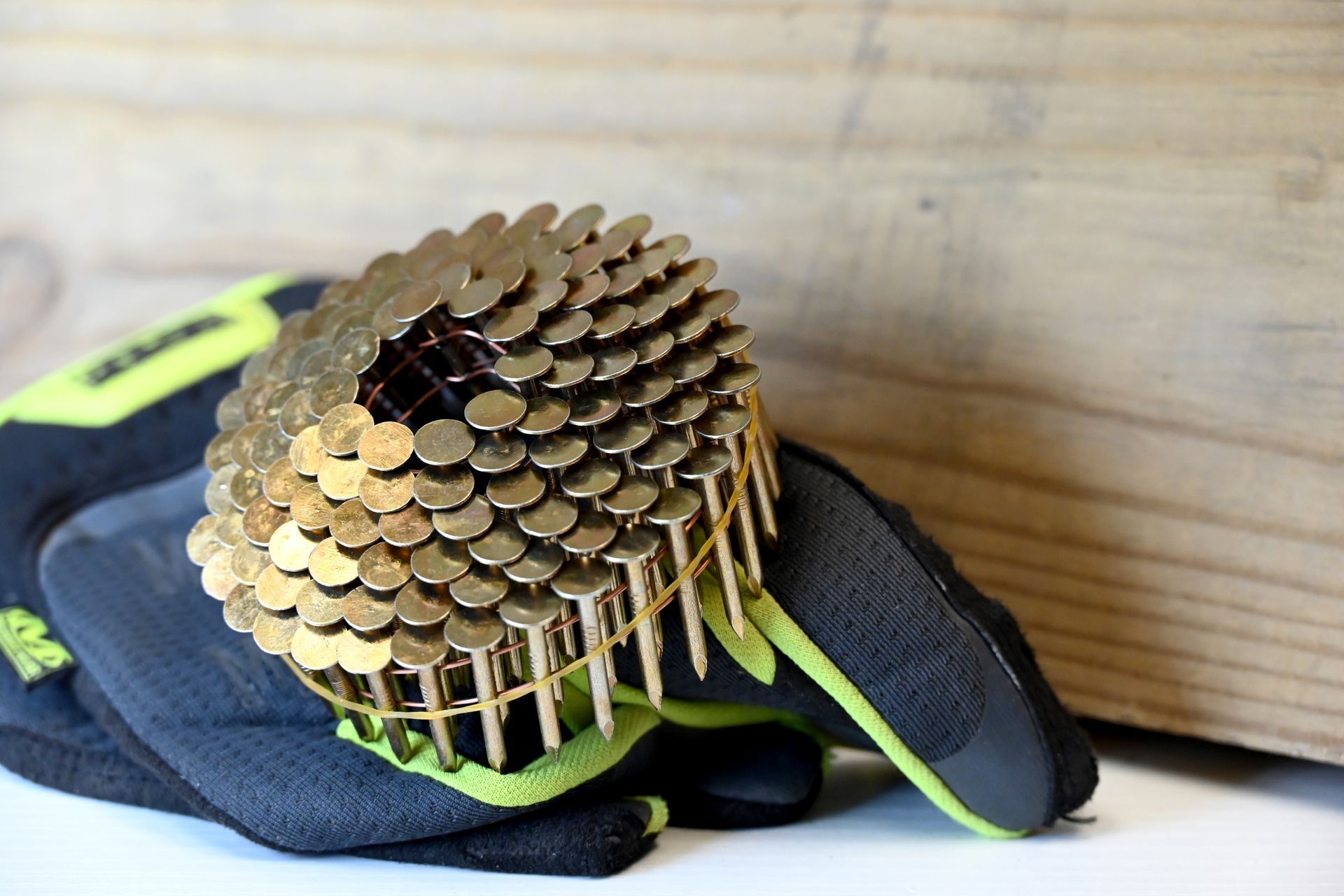 Close-up of a golden beehive-shaped sculpture on a black glove against a wooden wall.