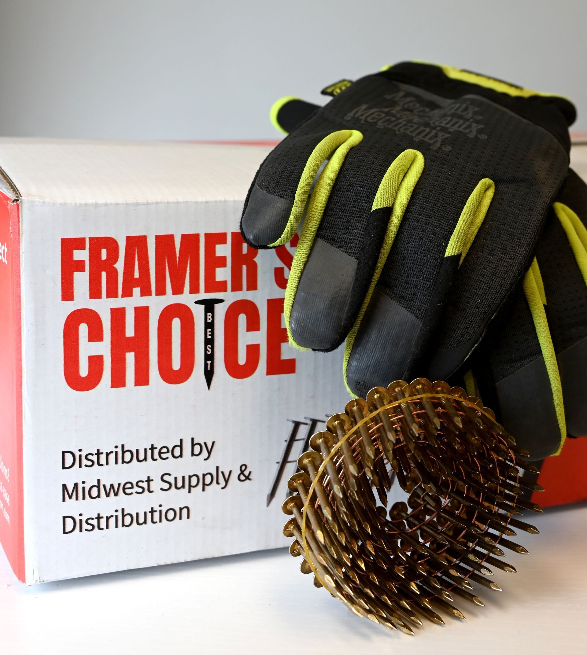 Work gloves beside a box labeled “Framer’s Choice” and a spiked metal wheel tool