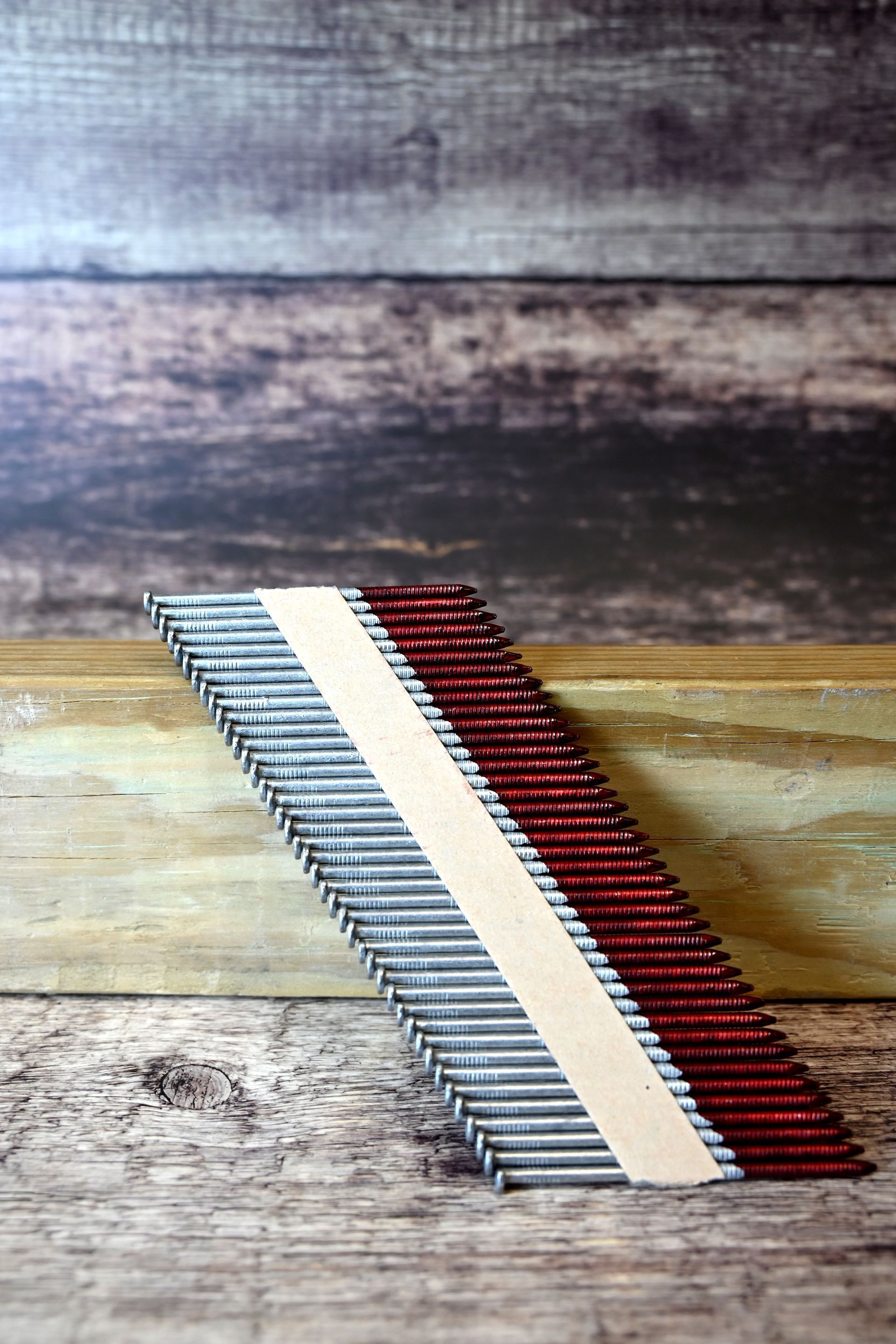 Close-up of a red, white, and gray striped woven ribbon on a rustic wood surface.