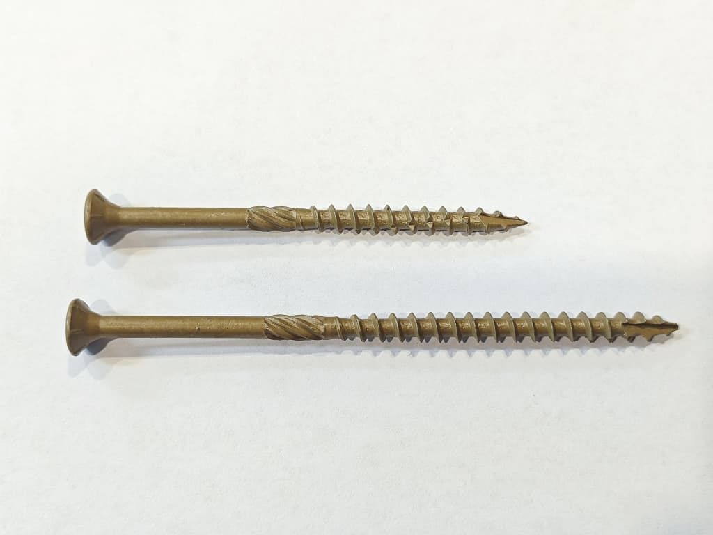 Two gold wood screws lying horizontally on a white background