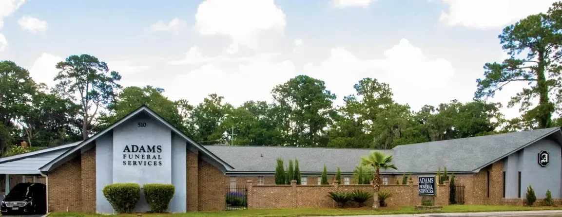 A brick building with a sign that says ' adams funeral home ' on it