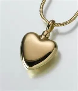 A gold heart shaped pendant on a chain on a white surface.