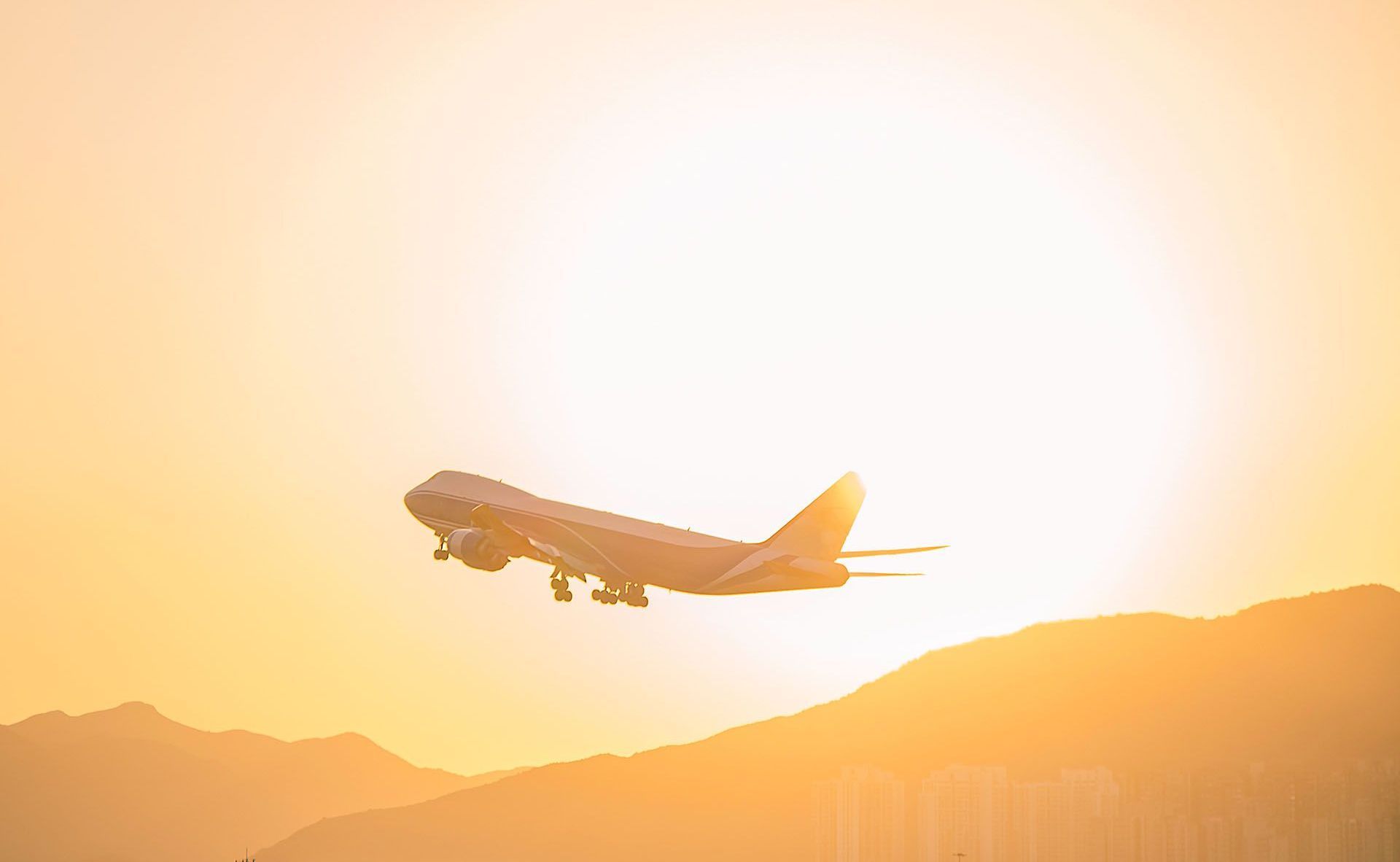 An airplane is flying over a mountain at sunset.