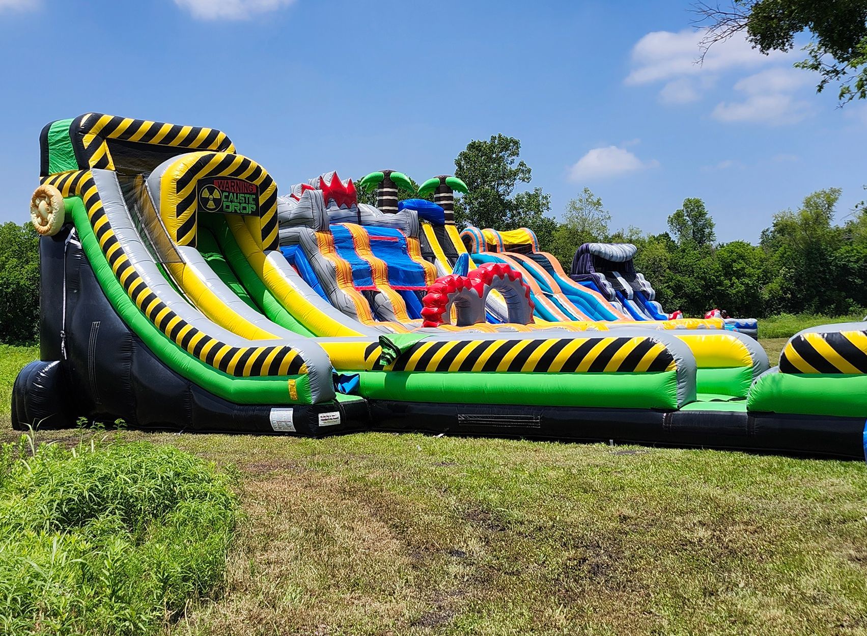 Large inflatable obstacle course on grass under a blue sky.