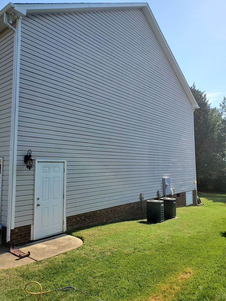 Side of a house with white siding, a white door, and a green lawn