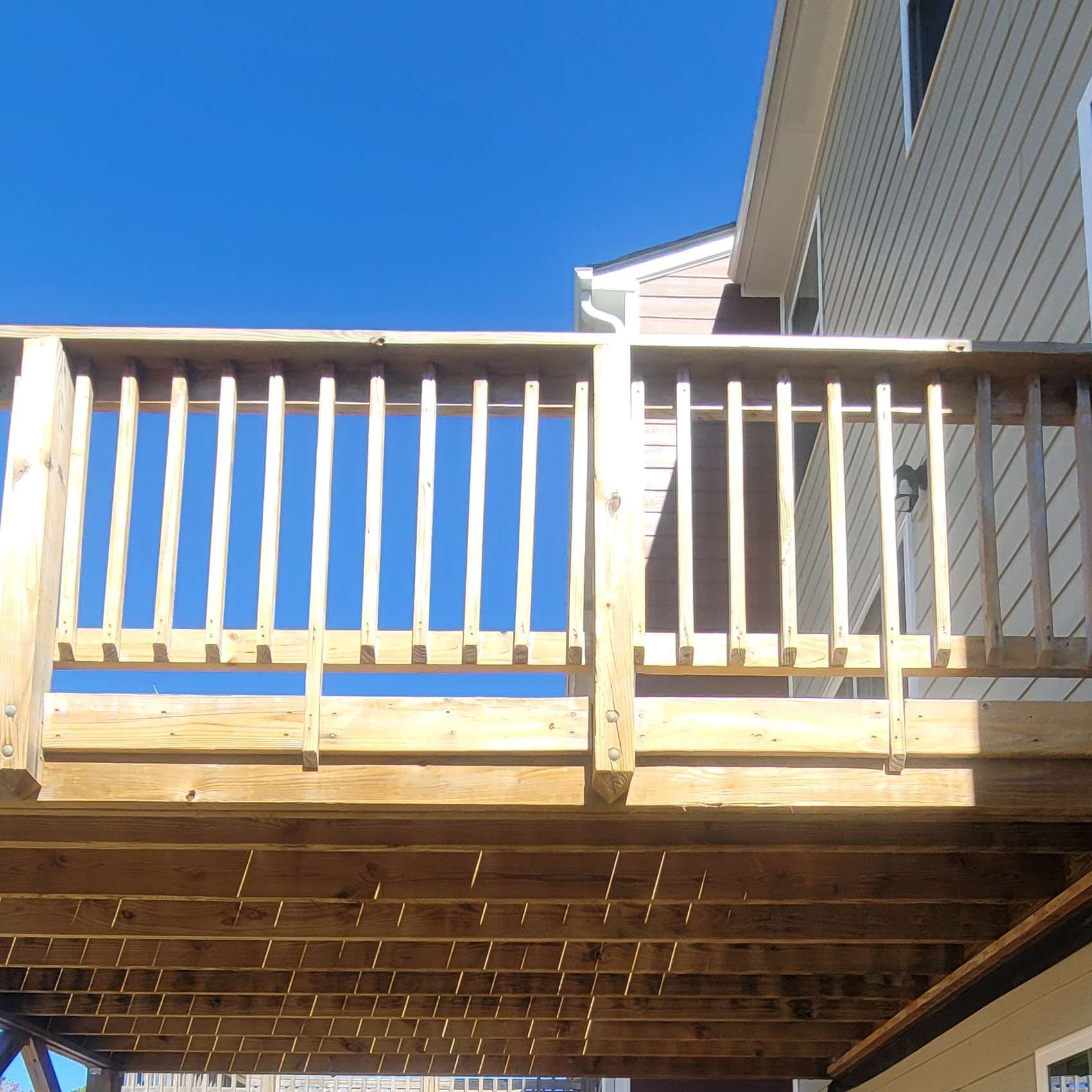 Wooden deck attached to a house, blue sky background.