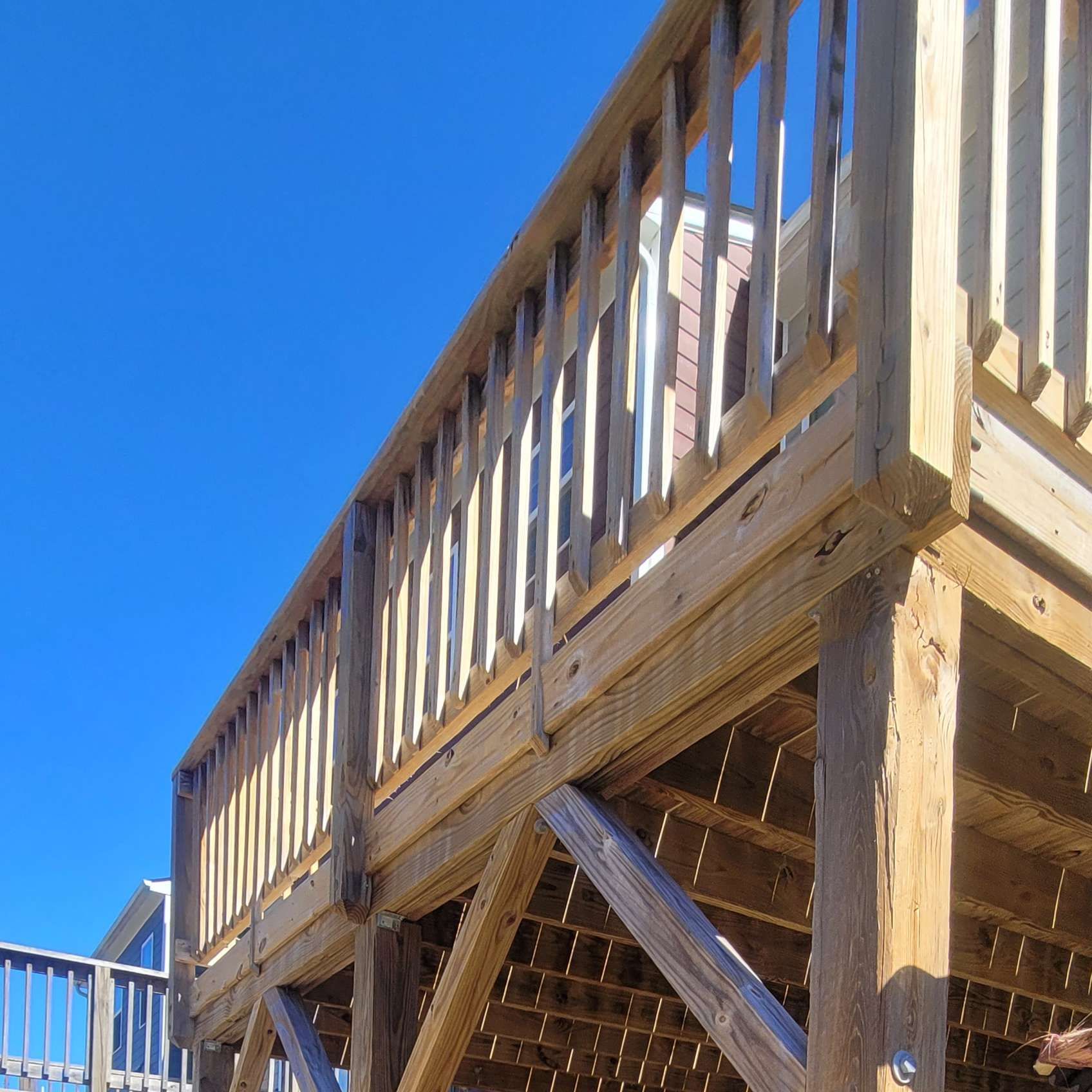 Wooden deck with railing against a blue sky.