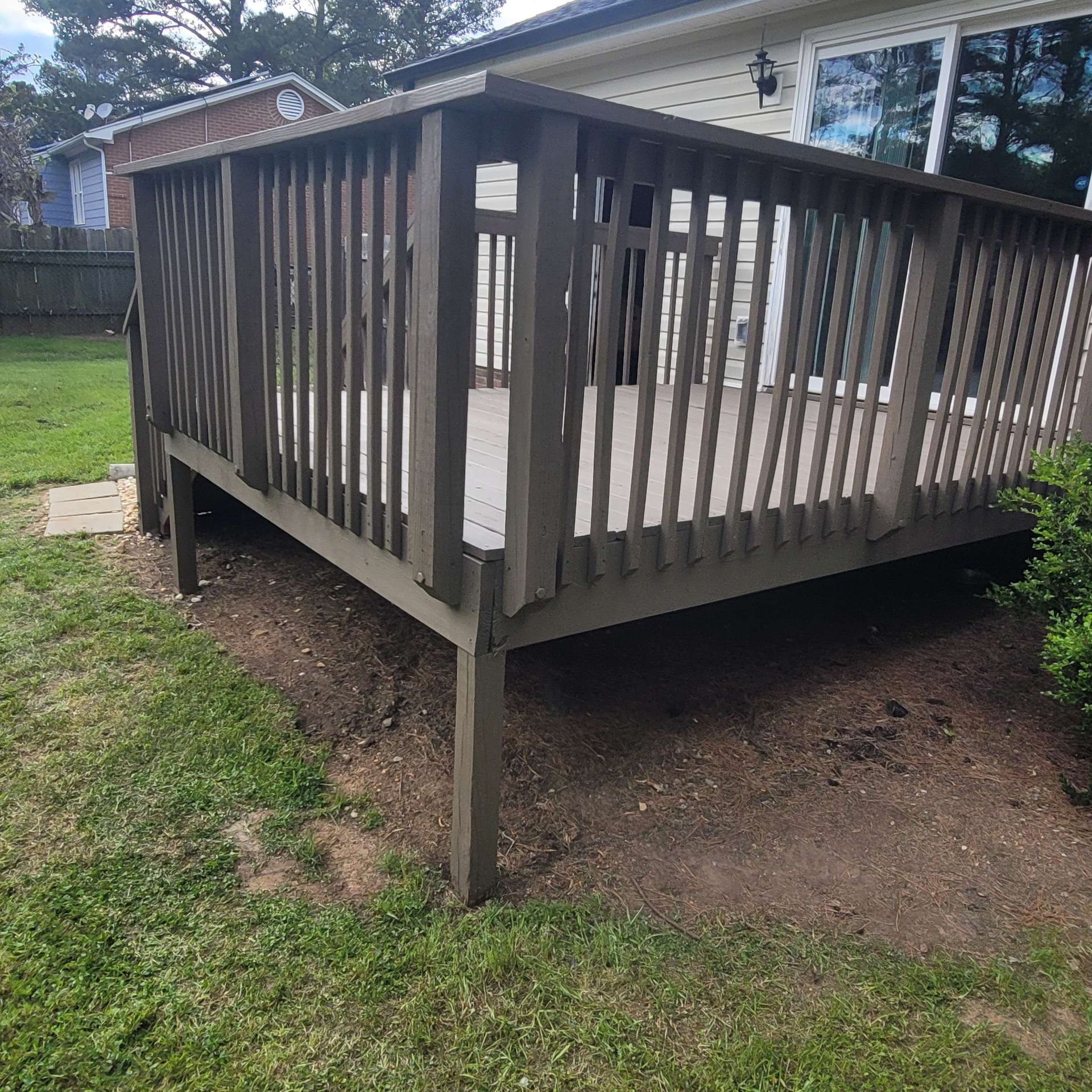 Wooden deck with railing and supports in a backyard setting