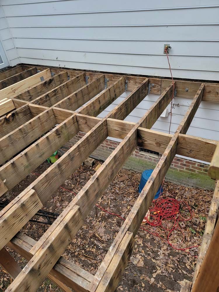 Deck frame, weathered wood, near a house, with fallen leaves.