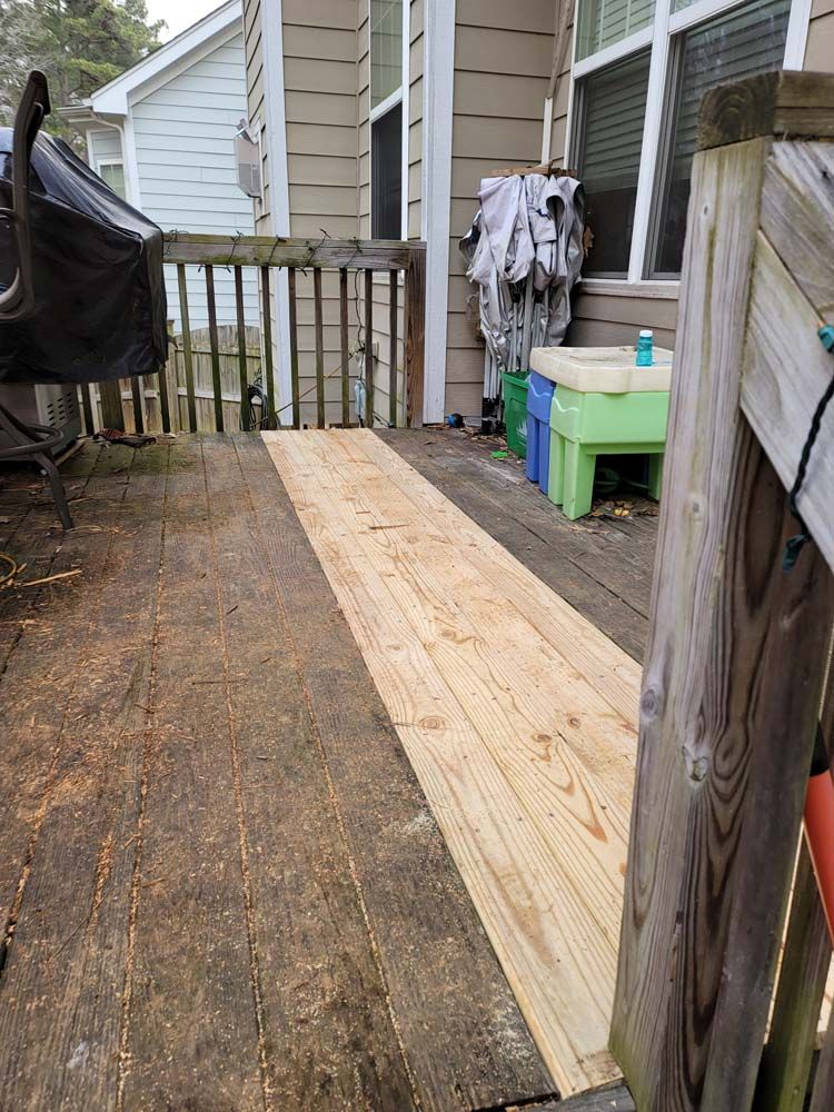 A weathered wooden deck with a newly constructed wooden walkway.