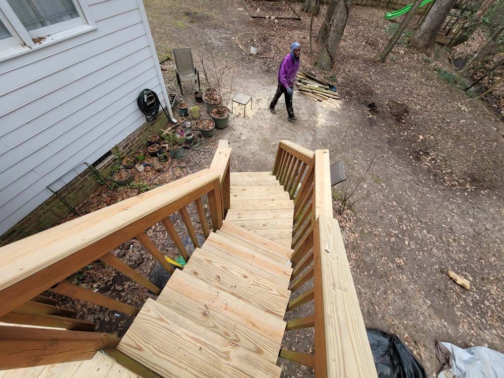 Wooden outdoor stairs leading down, person in purple walking in the yard.
