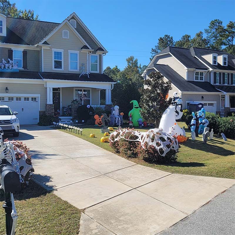 Houses decorated for Halloween with inflatable figures and pumpkins.