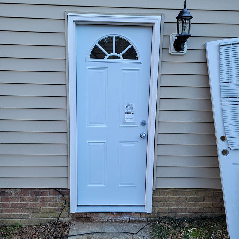 White door with arched glass panel and white trim on a beige building.