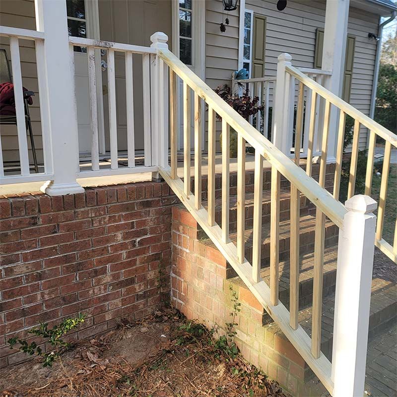 A wooden ramp with white railings, brick foundation, and house with shutters.