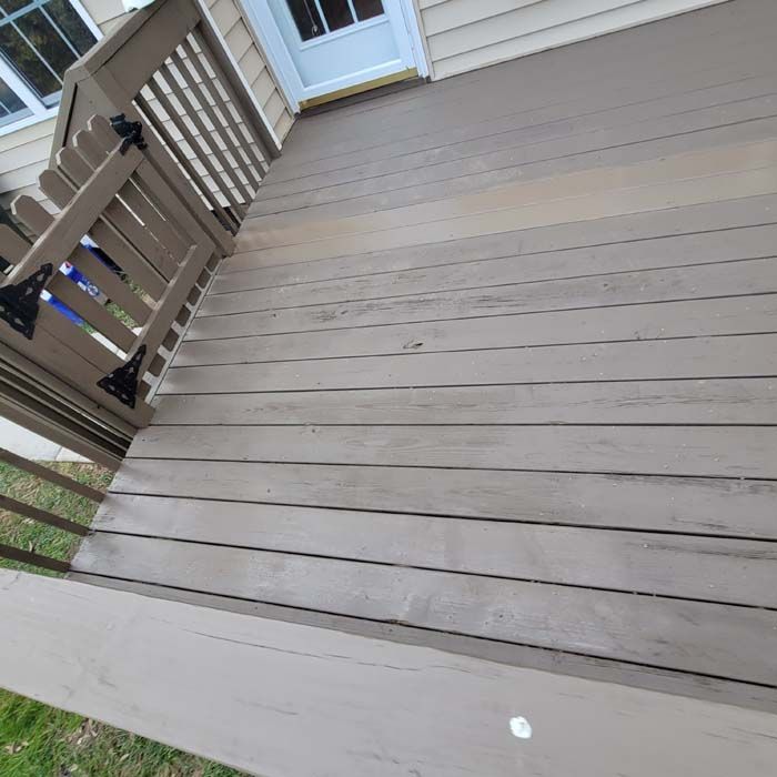 Wooden deck with a gate, painted in shades of brown and gray. The deck leads to a white door.