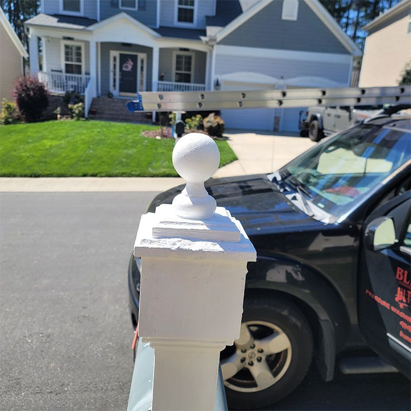 White painted pillar with a sphere top, parked in front of a house.