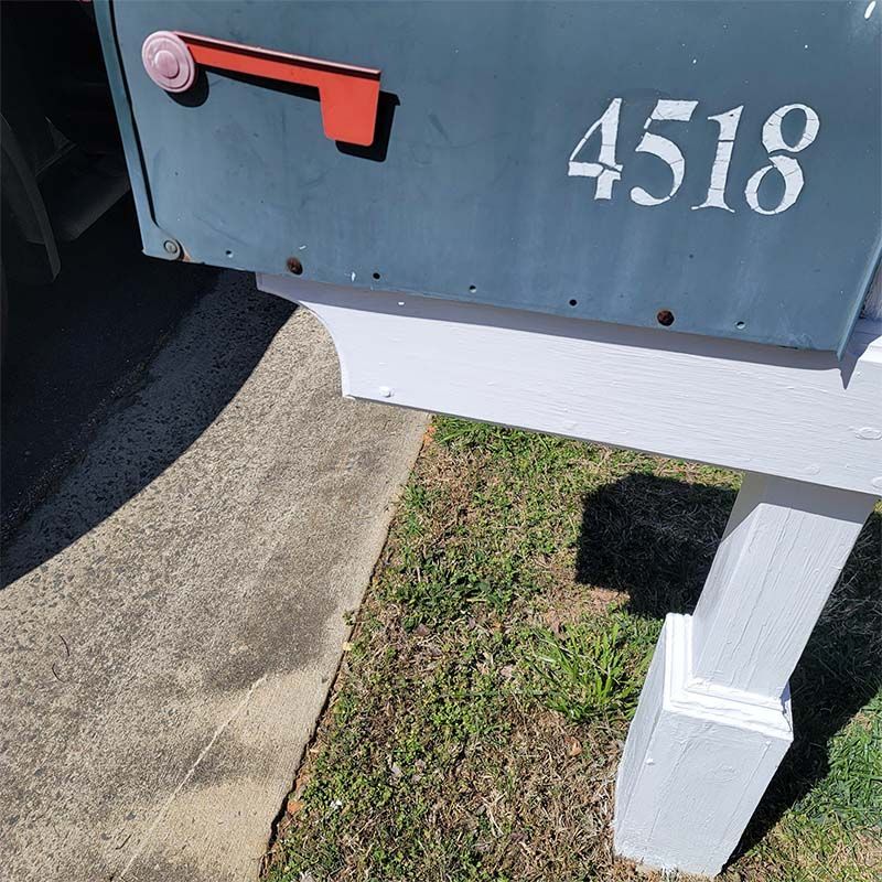 Mailbox with address 4518; blue box with red flag, white post, next to a sidewalk and grass.
