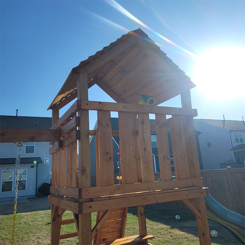 Wooden playset in backyard on a sunny day.