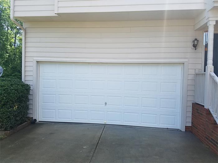 White garage door of a house, set in a concrete driveway.