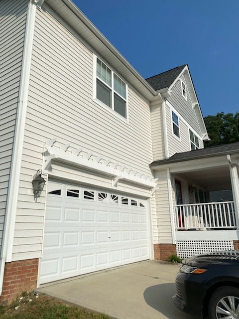 Two-story house with white siding, a white garage door, and a covered porch under a clear blue sky