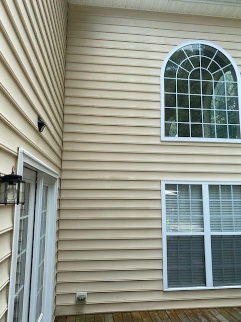 Beige vinyl siding on a house with white-framed windows