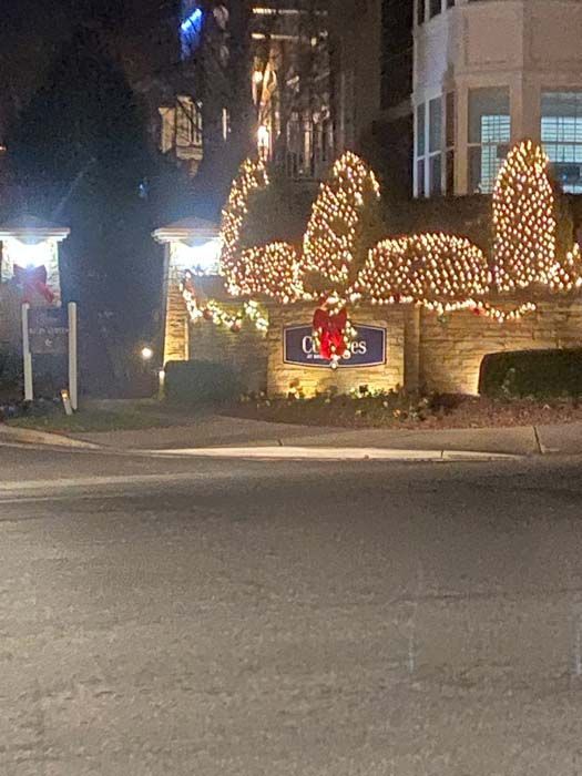 Nighttime view of an entrance sign with Christmas lights. 