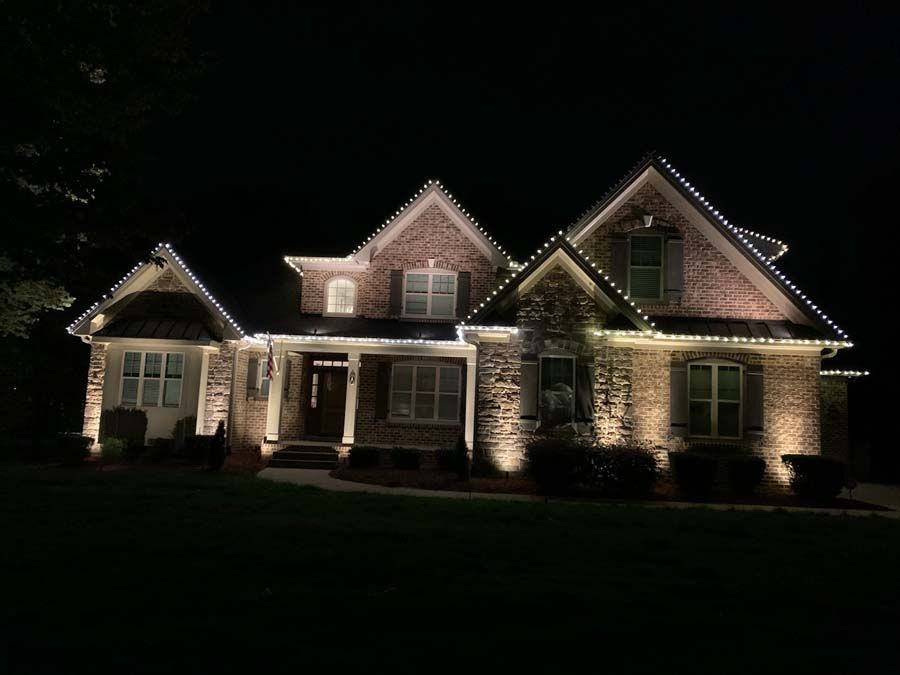 Brick house illuminated with white Christmas lights at night.