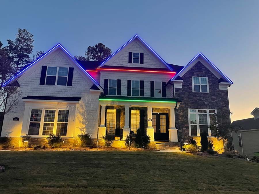 House decorated with blue, red, and green lights along the roofline, with warm yellow lighting on the ground.