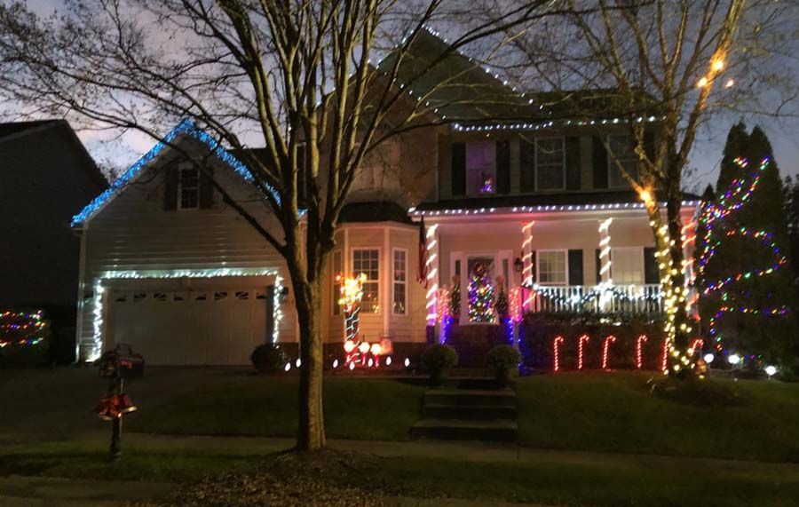 House decorated with Christmas lights, with white, blue, red, and yellow lights outlining the roof and porch.