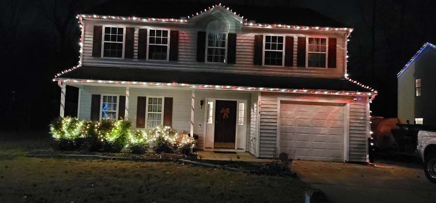 A two-story house decorated with Christmas lights at night.