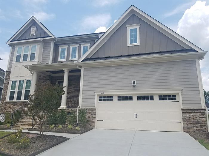 Two-story house with gray siding, a white garage door, and a stone facade.