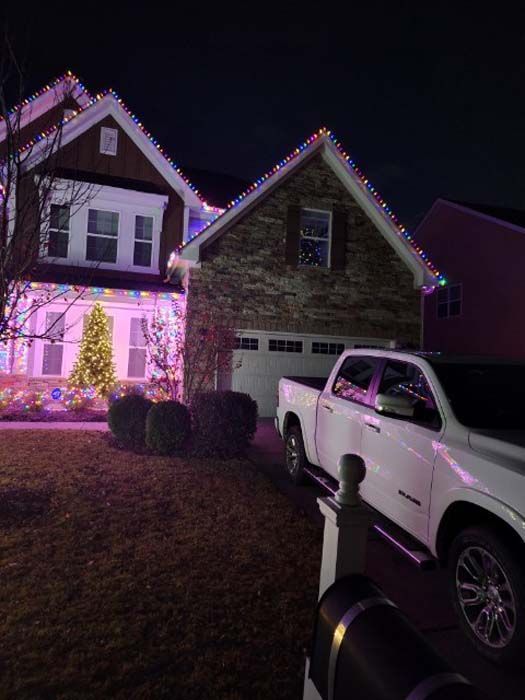 A house decorated with colorful Christmas lights; a white truck is parked in the driveway.
