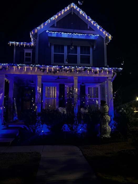 House decorated with blue Christmas lights at night.