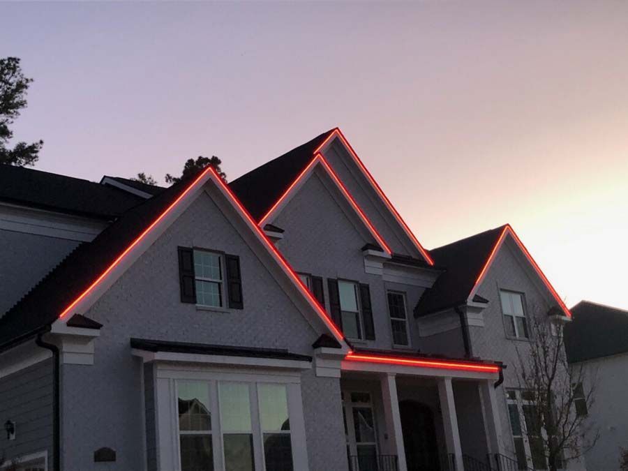 House with red lights outlining the roof against a dusky sky.