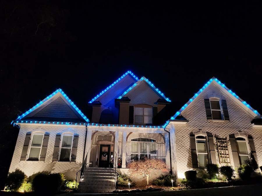 House with blue Christmas lights outlining the roof against a dark night sky.