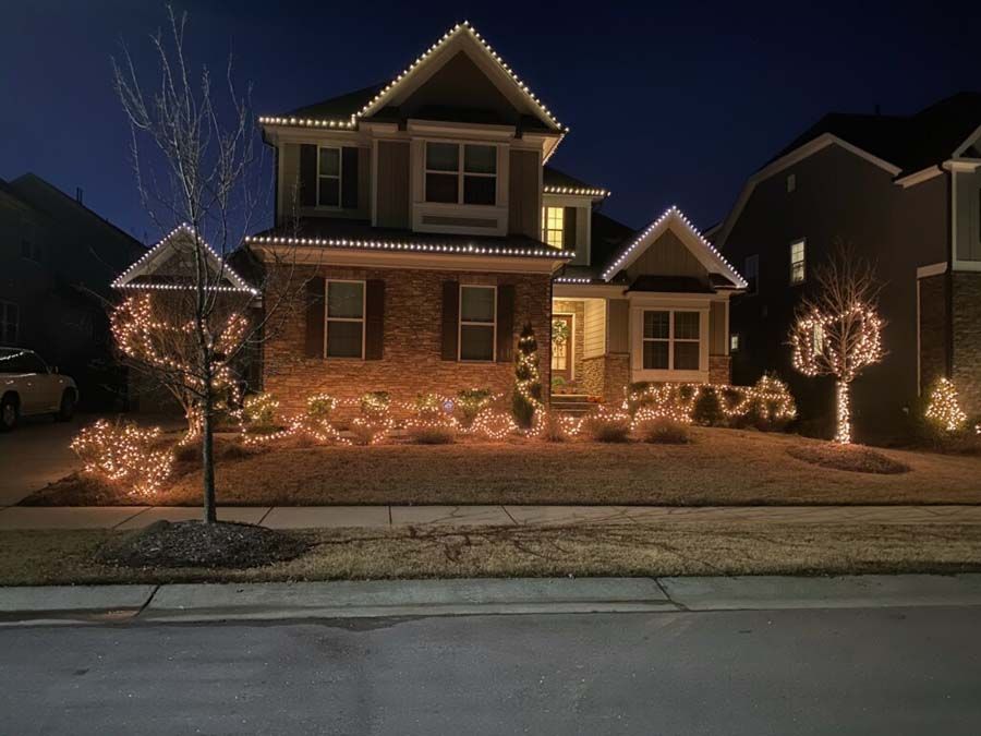 A two-story house decorated with Christmas lights at night.