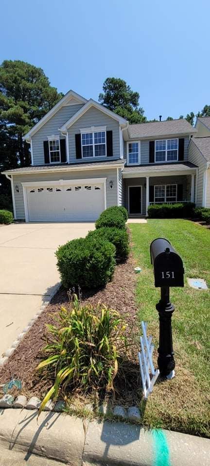 A two-story gray house with a white garage door and black mailbox with the number 151.