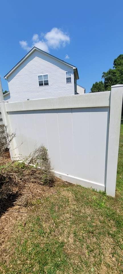 White fence with a house in the background and green grass.