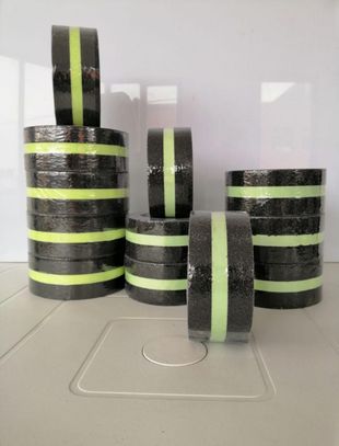 Cuatro pilas de anillos a rayas negras y verde neón sobre una mesa gris.