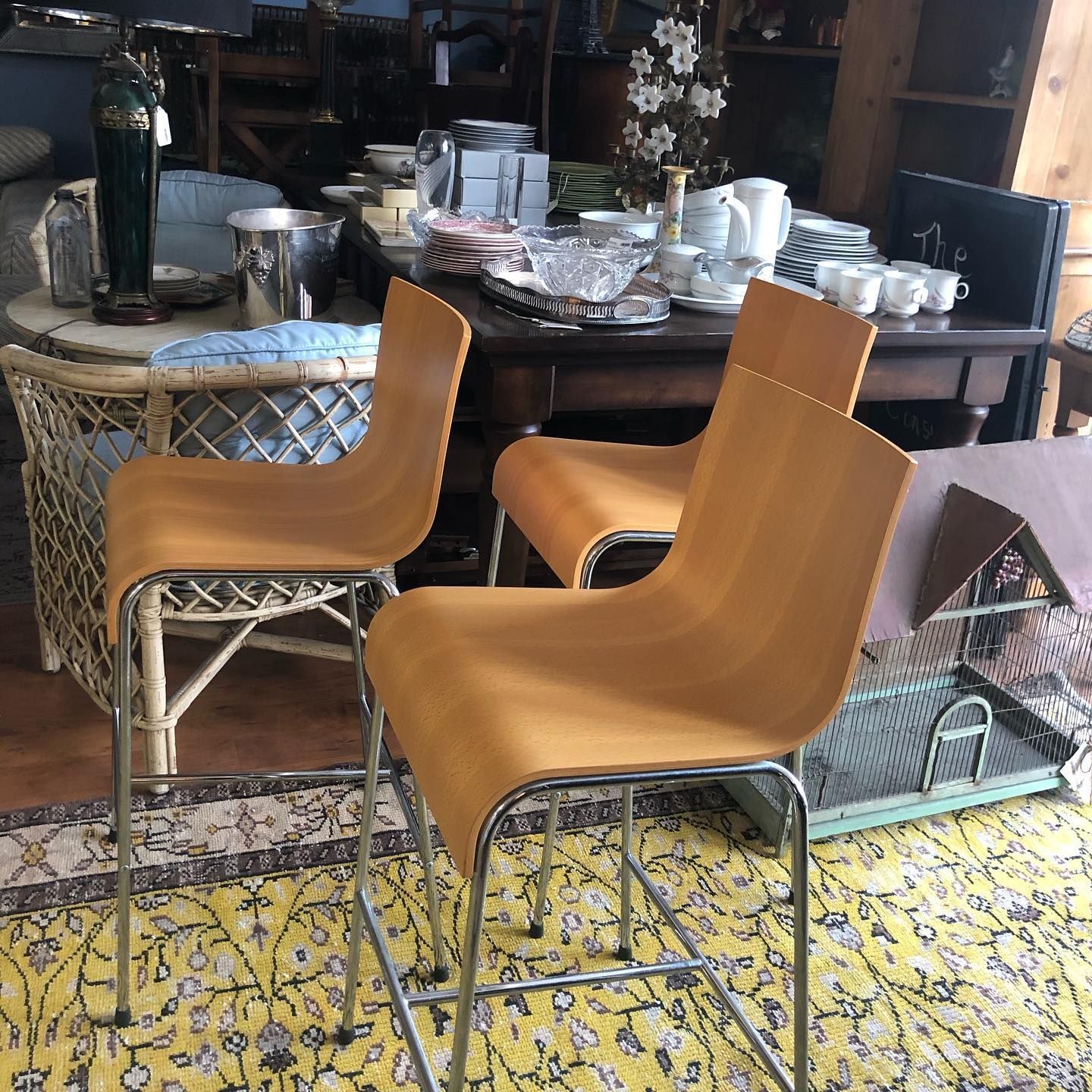 Three wooden chairs are sitting on a yellow rug in a room.