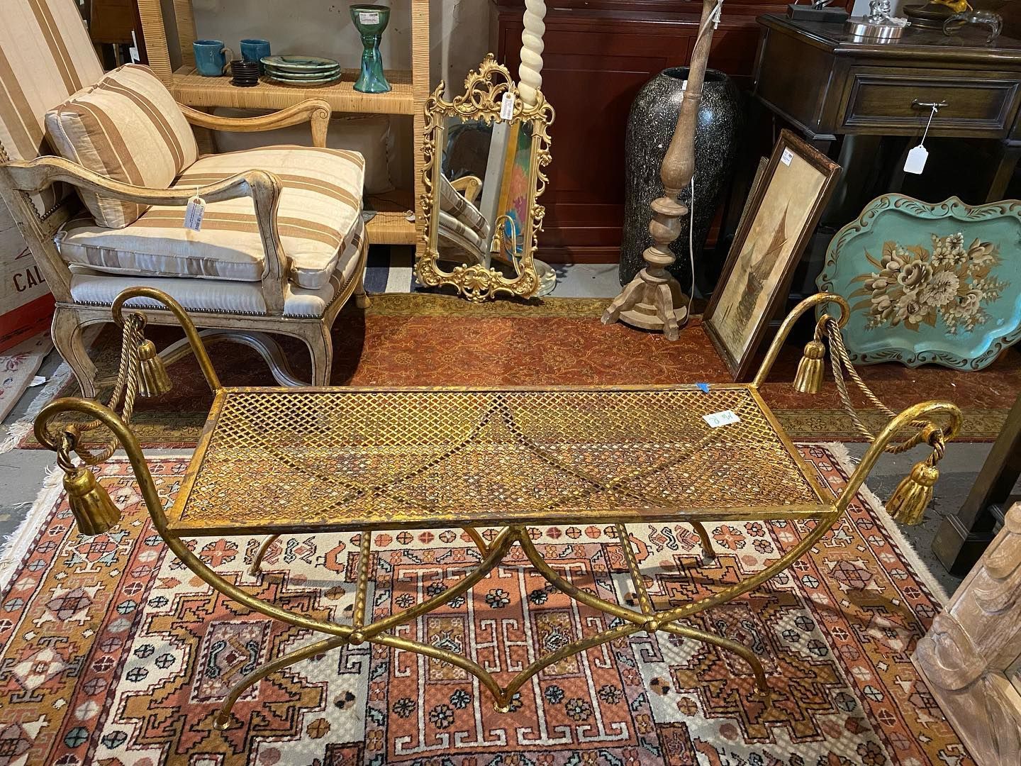 A brass bench is sitting on top of a rug in a room.