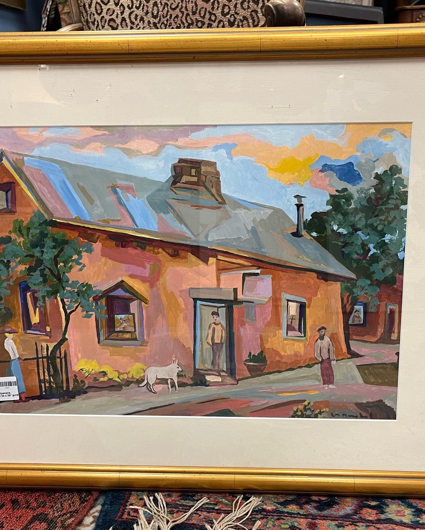 A framed painting of a house with a man standing in front of it.