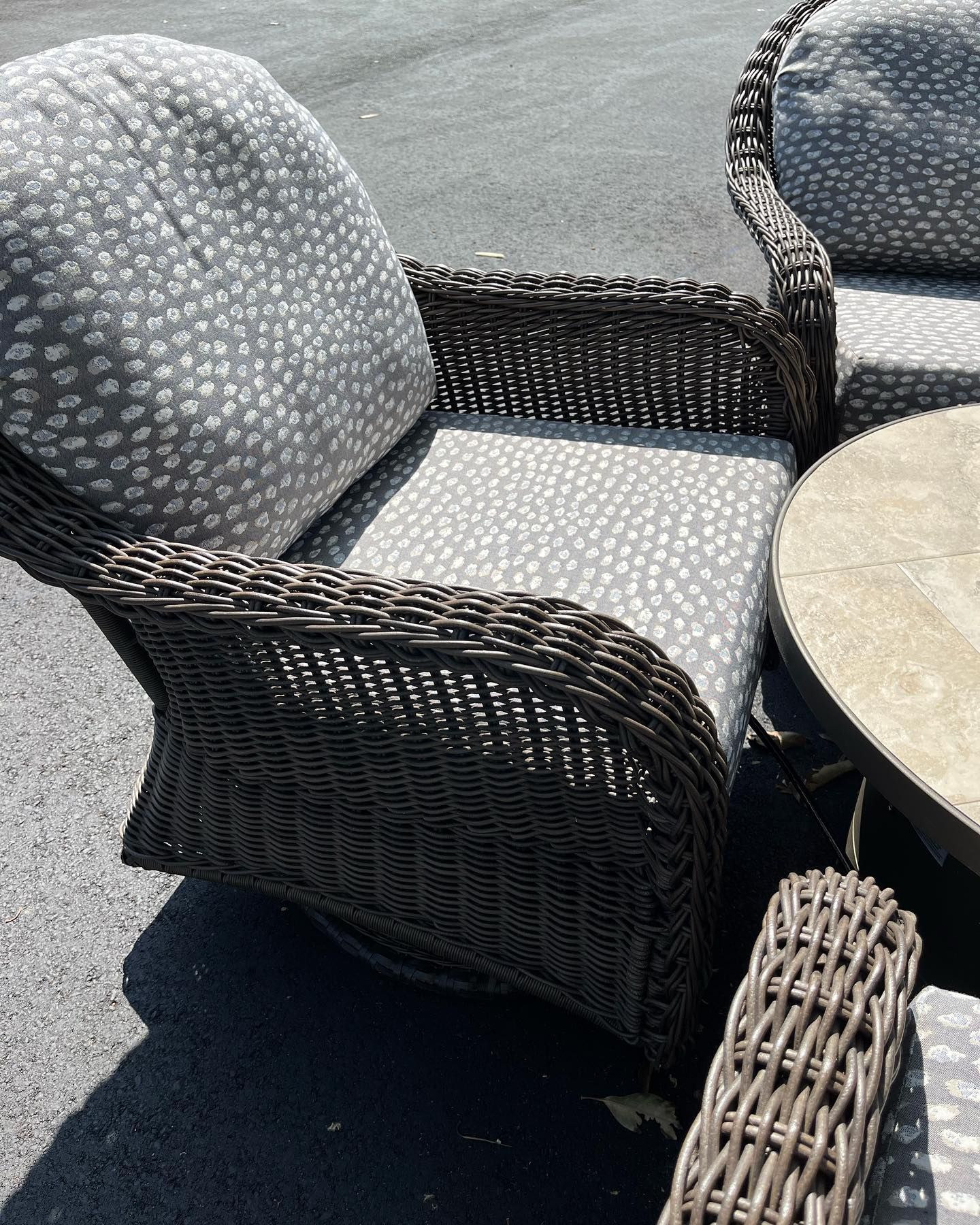 A wicker chair with a polka dot cushion sits next to a table.